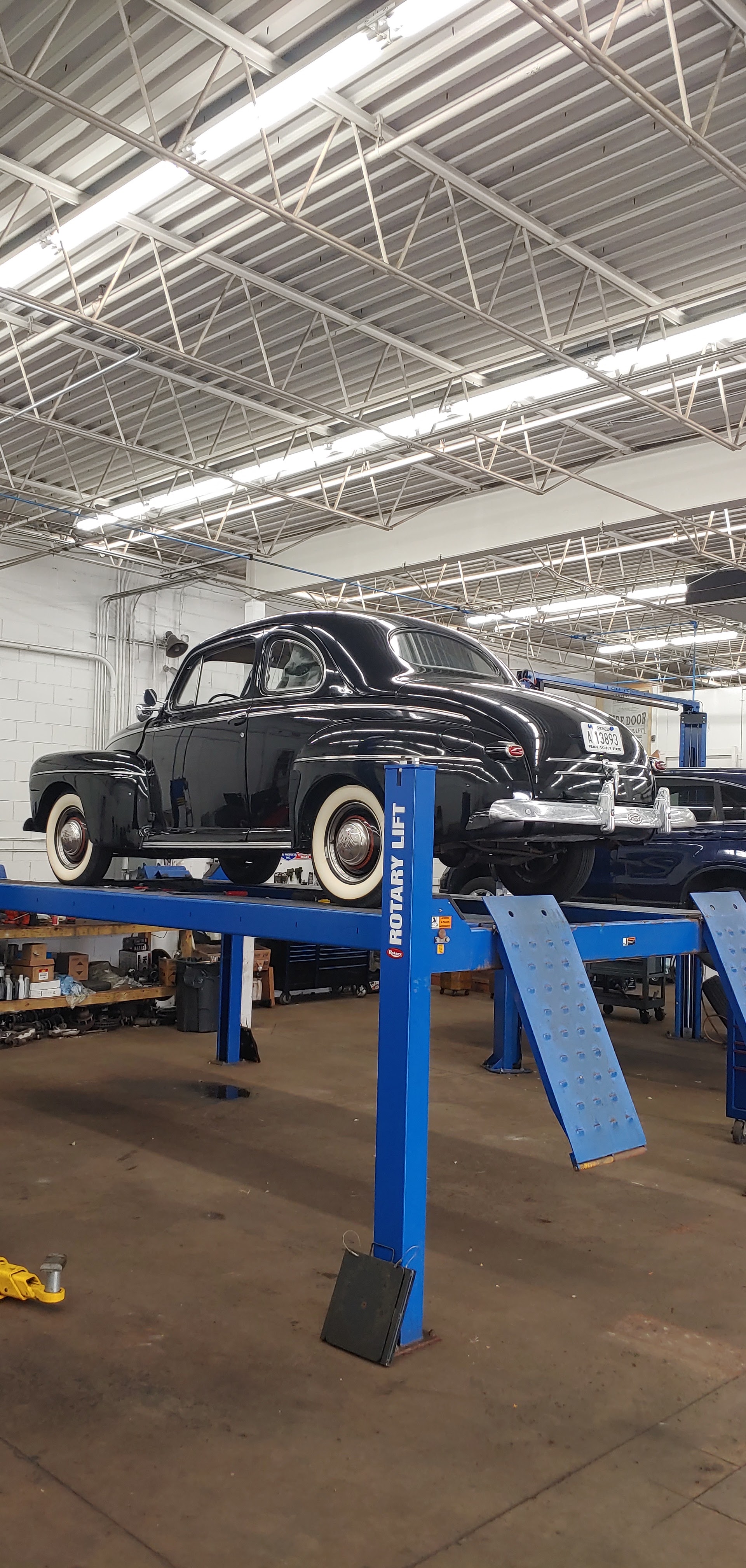 A black classic car on a lift inside Hake’s Auto workshop